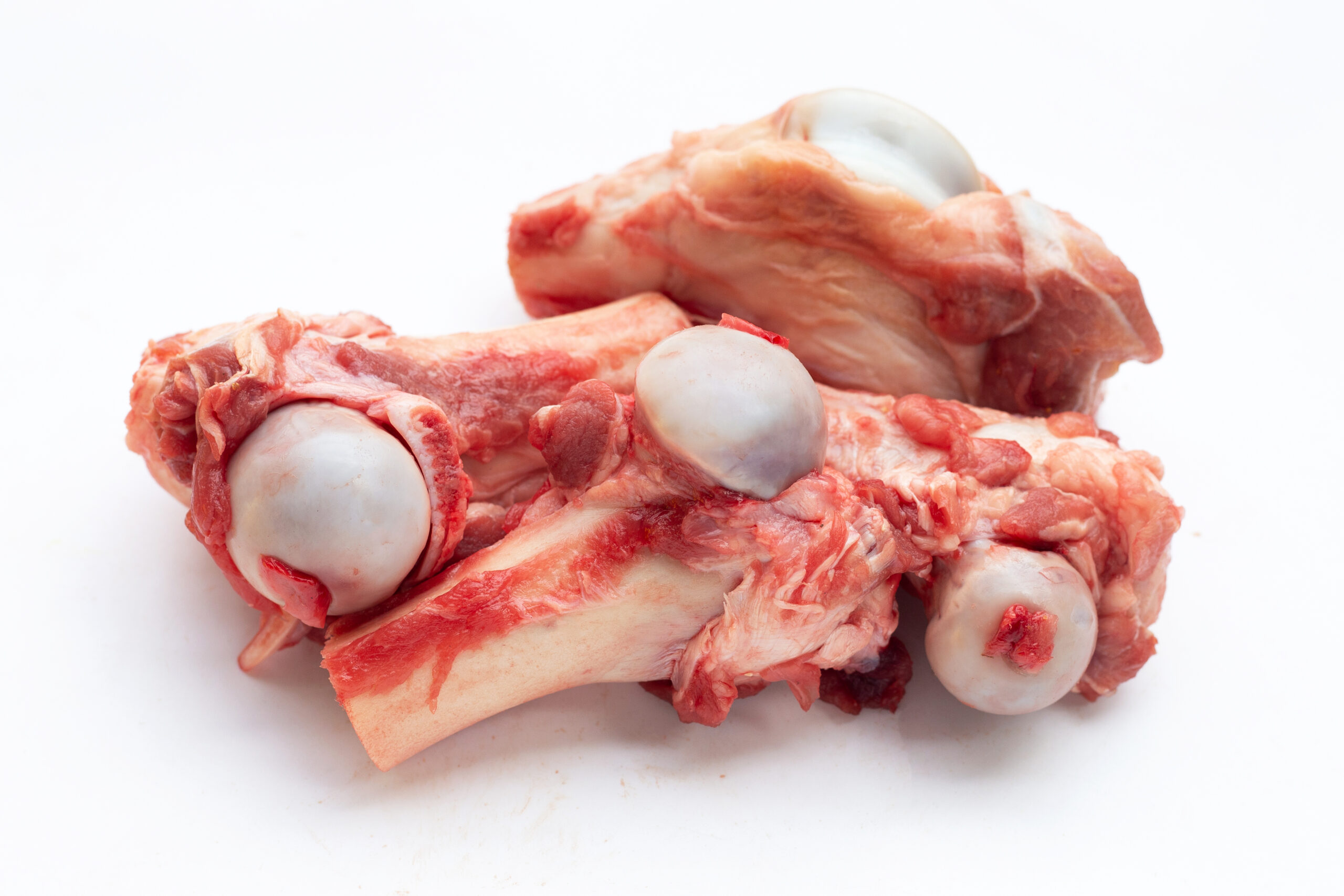 Raw pig bone in white bowl on white background. lamb testicles